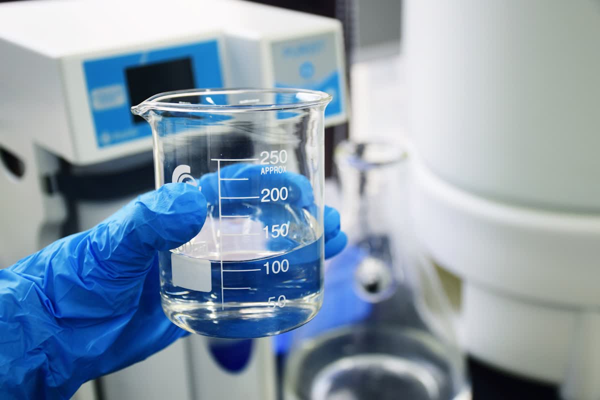 Laboratory quality control — a gloved hand holding a beaker